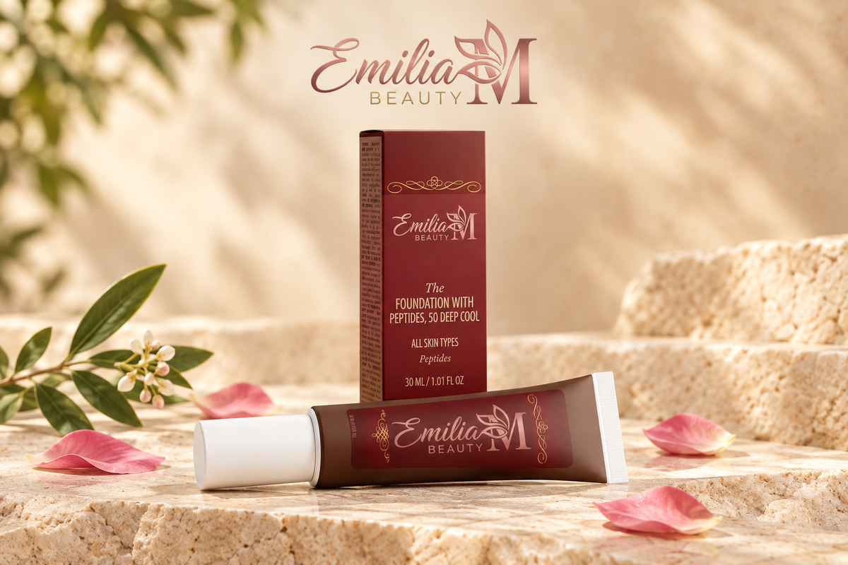 Emilia M Beauty Foundation with Peptides in 50 Deep Cool displayed with its burgundy box, flowers and pink petals in a warm beige setting